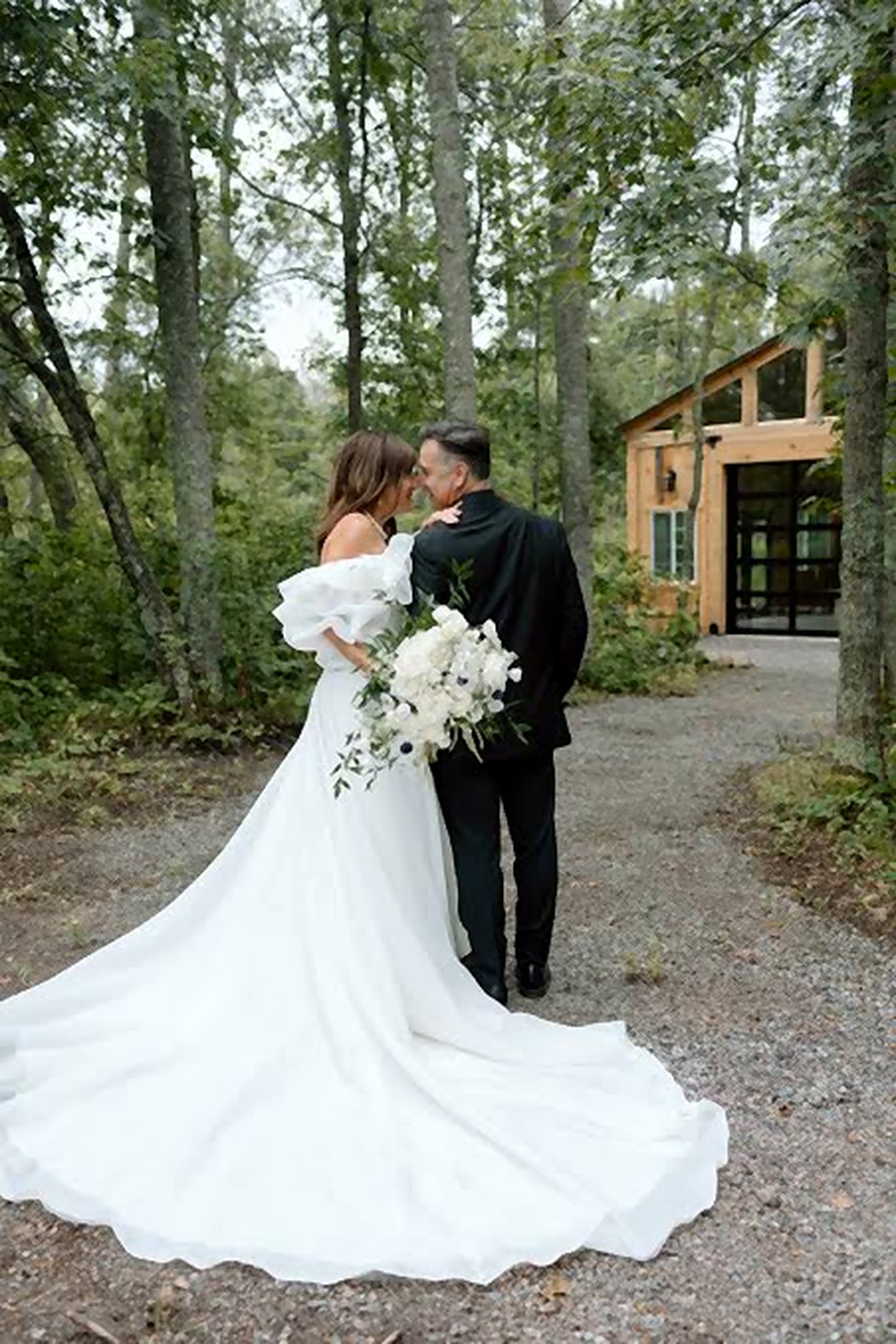 A couple walking hand in hand toward the timber cottage through the woods